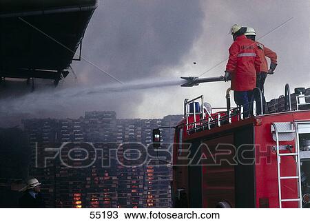 Stock Image - Fire fighters spraying water on fire . Fotosearch