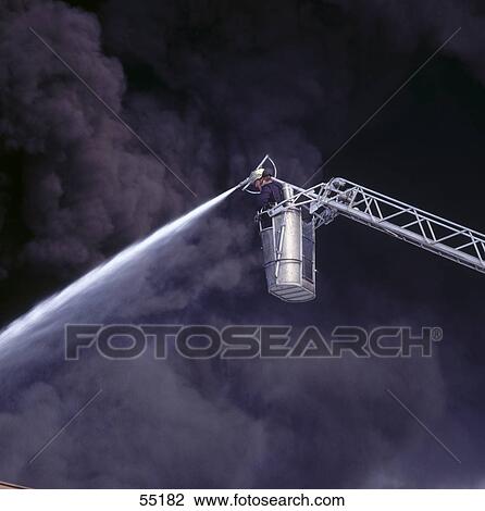 Low angle view of fireman spraying water on fire View Large Photo Image Stock Image - Low angle view of fireman spraying water on fire . Fotosearch