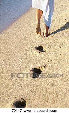 Stock Photo - Low section view of young woman walking on beach . Fotosearch
