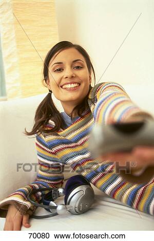 Portrait of teenage girl holding remote control and smiling View Large Photo Image Stock Image - Portrait of teenage girl holding remote control and smiling . Fotosearch