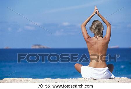 Rear view of young woman meditating on beach View Large Photo Image Stock Photography - Rear view of young woman meditating on beach . Fotosearch