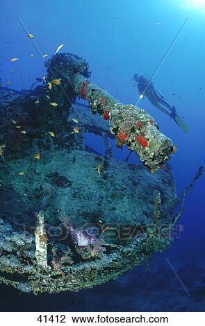 Stock Image - Scuba diver flashing light on shipwreck underwater . Fotosearch