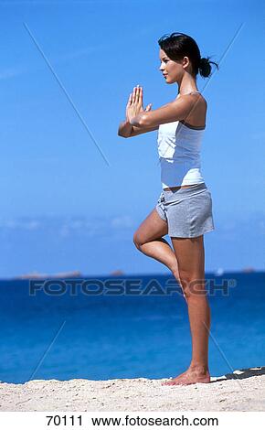 Stock Image - Side profile of young woman meditating on beach . Fotosearch