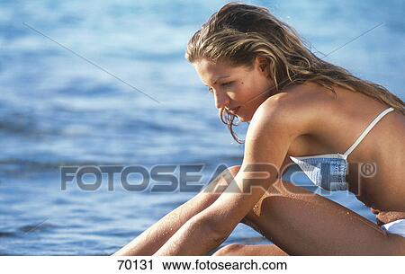 Stock Image - Side profile of young woman on the beach . Fotosearch