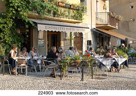 Tourists sitting at sidewalk cafe in town, Malcesine, Lake Garda, Italy View Large Photo Image Stock Image - Tourists sitting at sidewalk cafe in town, Malcesine, Lake Garda, Italy . Fotosearch