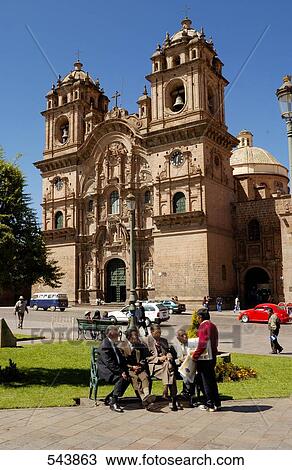 Stock Image - Tourists sitting on bench in front of church, Iglesia La Compania De Jesus, Cuzco, Cusco Region, Peru . Fotosearch