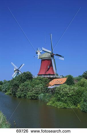 Stock Photograph - Traditional windmills at waterfront, East Frisia, Greetsiel, Germany . Fotosearch