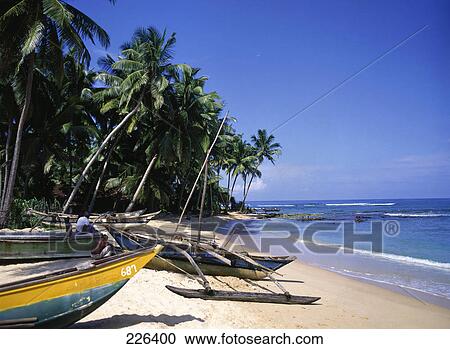 Stock Image - Two fishermen with boats on beach . Fotosearch