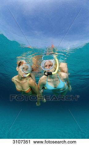 Stock Image - Two young woman snorkeling, Bali, Indian Ocean, underwater shot . Fotosearch