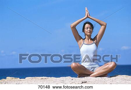 Young woman meditating on beach View Large Photo Image Stock Photo - Young woman meditating on beach . Fotosearch