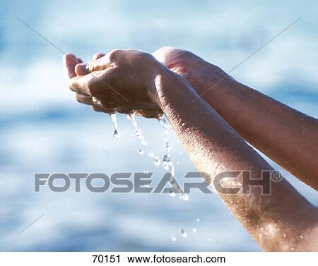 Stock Image - Young woman's hands dropping water . Fotosearch