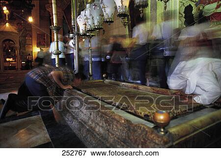 Stock Photo - Blurred view of people praying at tomb . Fotosearch