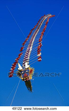 Stock Image - Dragon head kite flying against blue sky . Fotosearch