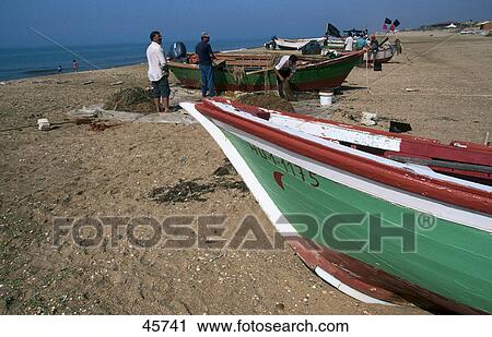 Stock Image - Fishermen with fishing boats at beach, La Antilla, Costa de la Luz, Andalusia, Spain . Fotosearch