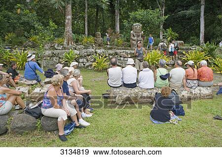 Stock Photo - Group of tourists vistiting Polynesian ancestral figures, Puamau, Hiva Oa, French Polynesia . Fotosearch