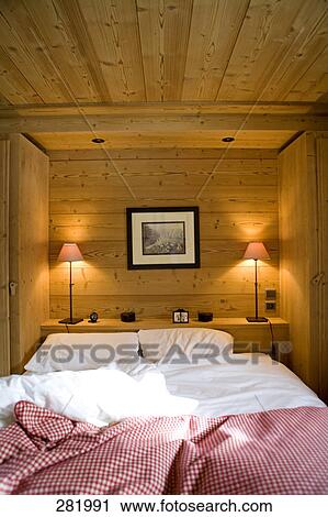 Stock Image - Interiors of bedroom lit up with lamps, France . Fotosearch