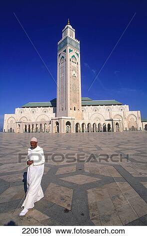 Stock Photo - Man walking in front of mosque, Grande Mosque Hassan II, Casablanca, Morocco . Fotosearch
