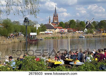 People sitting at restaurant with church in background, Havel River, Heilig-Geist-Kirche, Werder, Brandenburg, Germany View Large Photo Image Stock Image - People sitting at restaurant with church in background, Havel River, Heilig-Geist-Kirche, Werder, Brandenburg, Germany . Fotosearch