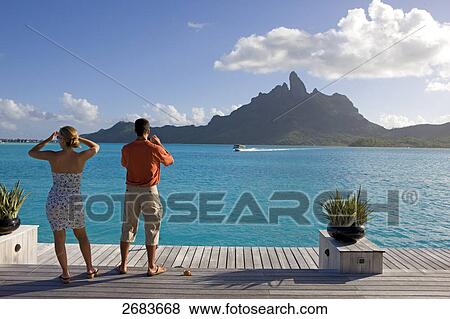 Rear view of couple standing at harbor near resort, Saint-Regis Resort, Bora Bora, Society Island, French Polynesia View Large Photo Image Stock Photo - Rear view of couple standing at harbor near resort, Saint-Regis Resort, Bora Bora, Society Island, French Polynesia . Fotosearch