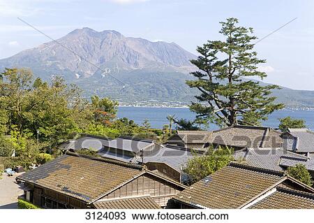 Stock Image - Rooftops in Kagoshima, volcano Sakurajima in the background, Japan, high angle view . Fotosearch