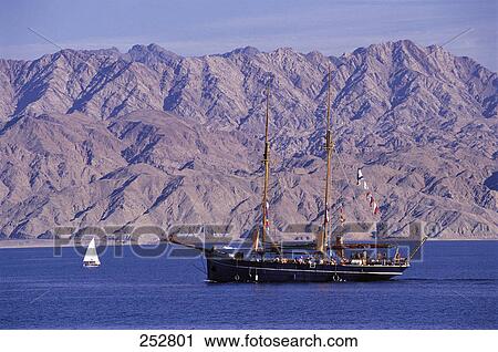 Stock Image - Sailboat in sea with mountain range in background . Fotosearch