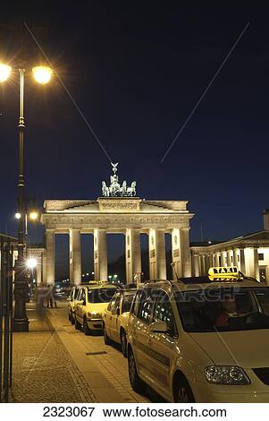 Stock Photo - Taxis near memorial gate lit up at dusk, Brandenburg Gate, Berlin, Germany . Fotosearch