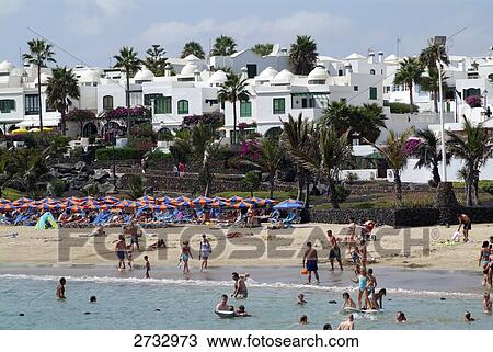 Stock Image - Tourists on beach, Costa Teguise, Playa des Cucharas, Lanzarote, Canary Islands, Spain . Fotosearch