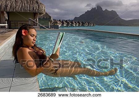 Woman reading magazine while relaxing in pool at resort, Society Islands, Bora Bora, French Polynesia View Large Photo Image Stock Photo - Woman reading magazine while relaxing in pool at resort, Society Islands, Bora Bora, French Polynesia . Fotosearch