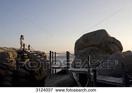 Woman taking pictures at a rocky coast, Nha Trang, Vietnam  View Large Photo Image Stock Photo - Woman taking pictures at a rocky coast, Nha Trang, Vietnam . Fotosearch