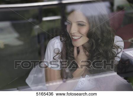 Stock Photograph - Young woman looking out of the window . Fotosearch