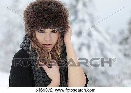 Stock Image - Young woman with scarf and cap in snow . Fotosearch
