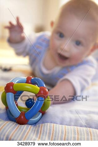 Stock Photo - Baby reaching for toy . Fotosearch