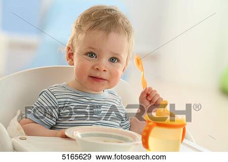 Baby sitting at table View Large Photo Image Stock Photo - Baby sitting at table . Fotosearch