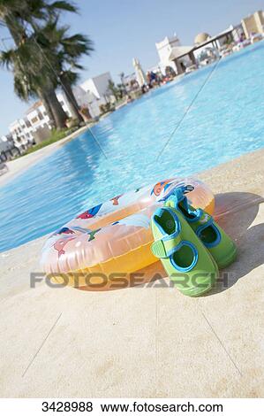 Bathing shoes and inflatable ring by pool side, slanted View Large Photo Image Stock Photo - Bathing shoes and inflatable ring by pool side, slanted . Fotosearch