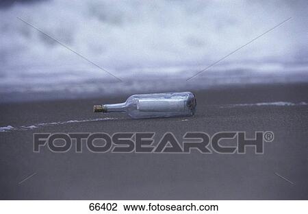 Stock Image - Bottle with message on beach . Fotosearch