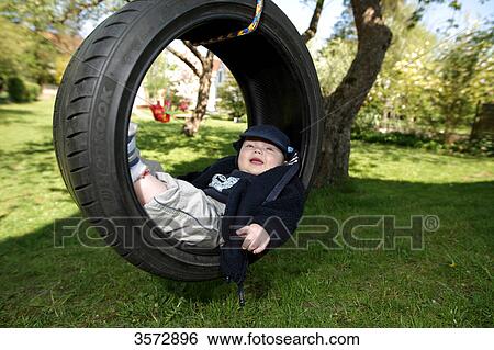 Stock Photograph - Boy lying in tyre swing . Fotosearch