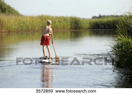 Stock Photo - Boy paddling on river Alte Sorge, Bergenhusen, Schleswig-Holstein, Germany, Europe . Fotosearch