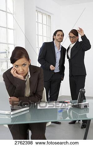 Stock Photo - Businesswoman looking bored with two businesspeople standing in background . Fotosearch