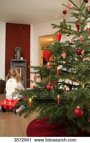 Stock Image - Christmas tree and girl on bobbycar in lving room . Fotosearch