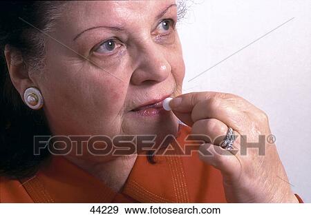 Stock Photo - Close-up of a woman taking medicine . Fotosearch