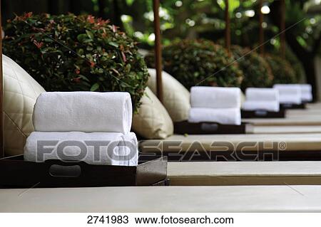 Stock Image - Close-up of bundles of towels on lounge chairs . Fotosearch