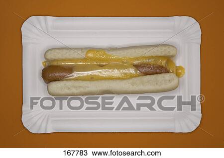 Stock Image - Close-up of hot dog and mustard sauce on paper plate . Fotosearch