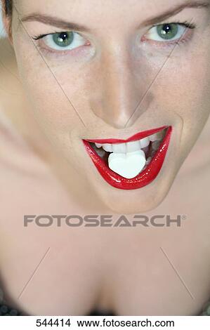 Picture - Close-up of young woman eating heartshape candy . Fotosearch