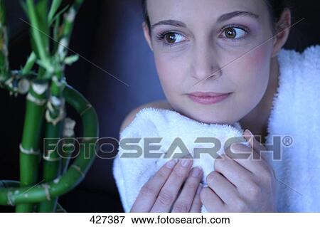 Stock Photo - Close-up of young woman looking at a bamboo plant . Fotosearch