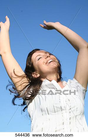 Close-up of young woman raising her hands and smiling View Large Photo Image Stock Photograph - Close-up of young woman raising her hands and smiling . Fotosearch