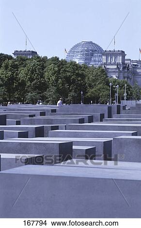 Picture - Concrete steles at memorial with buildings in background, Monument To The Murdered Jews Of Europe, Berlin, Germany . Fotosearch