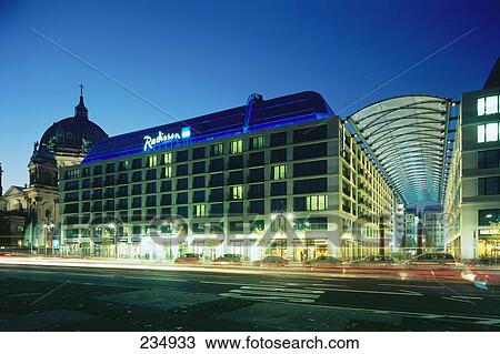 Stock Image - Facade of lit up hotel at dusk, Radisson SAS Hotel, Alexanderplatz, Berlin, Germany . Fotosearch