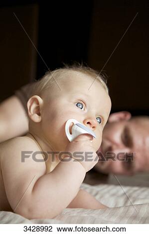 Father and son lying on a bed View Large Photo Image Stock Image - Father and son lying on a bed . Fotosearch