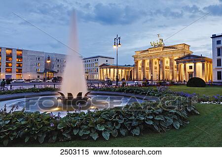 Stock Photography - Fountain with buildings lit up at dusk, Brandenburg Gate, Berlin, Germany . Fotosearch