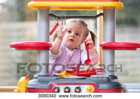 Stock Image - Girl cooking in a play kitchen . Fotosearch